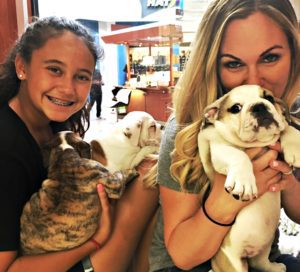 Mom and a daughter holding puppies in a pet store.